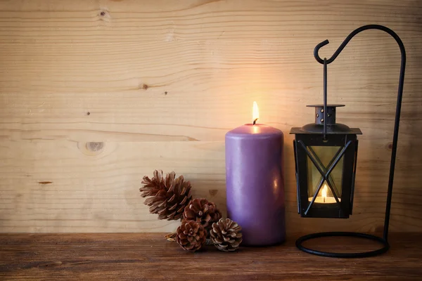 Linterna Vintage con vela ardiente y conos de pino sobre mesa de madera. imagen filtrada —  Fotos de Stock