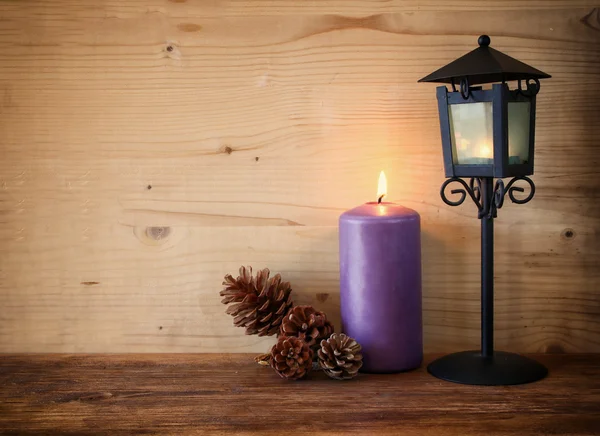 Linterna Vintage con vela ardiente y conos de pino sobre mesa de madera. imagen filtrada —  Fotos de Stock