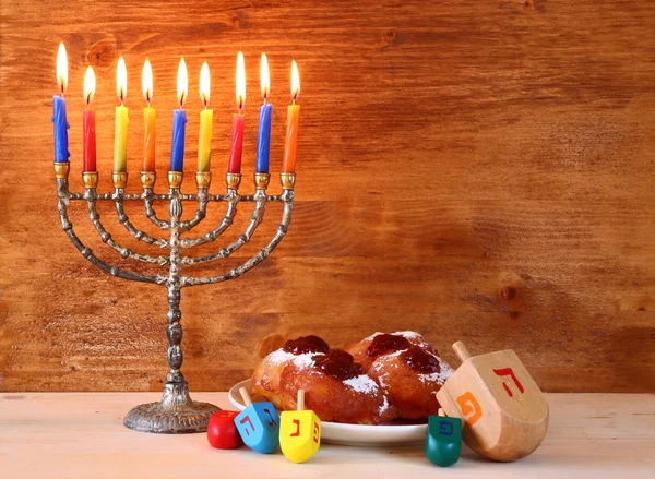 Joodse vakantie Hanukkah met menora, donuts en houten dreidels (spinnen boven). Retro gefilterde afbeelding — Stockfoto