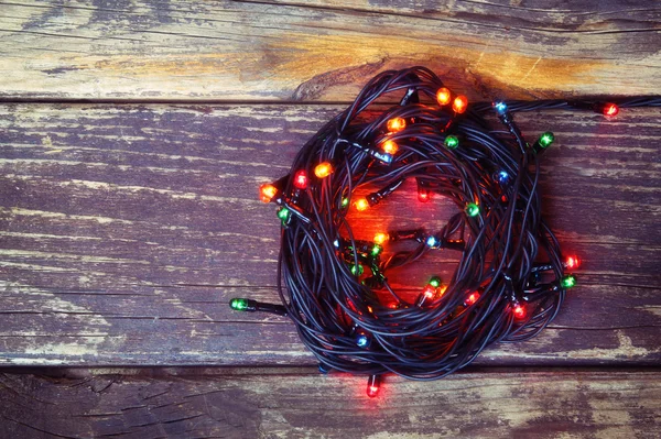 Luzes de Natal coloridas em fundo rústico de madeira. imagem filtrada — Fotografia de Stock