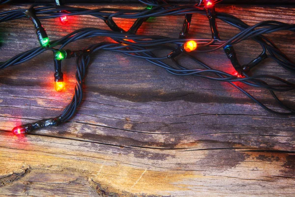 Colorate luci di Natale su sfondo rustico in legno. immagine filtrata — Foto Stock