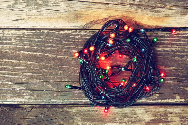 Luzes de Natal coloridas em fundo rústico de madeira. imagem filtrada — Fotografia de Stock