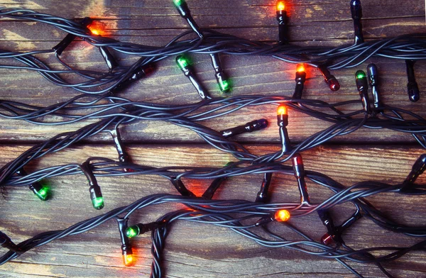Luzes de Natal coloridas em fundo rústico de madeira. imagem filtrada — Fotografia de Stock
