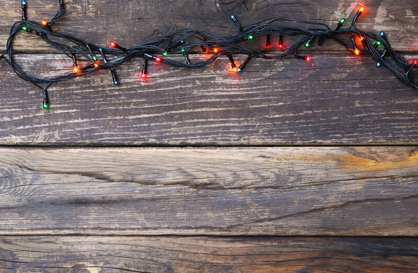 Luzes de Natal coloridas em fundo rústico de madeira. imagem filtrada — Fotografia de Stock