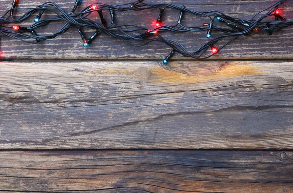 Luzes de Natal coloridas em fundo rústico de madeira. imagem filtrada — Fotografia de Stock