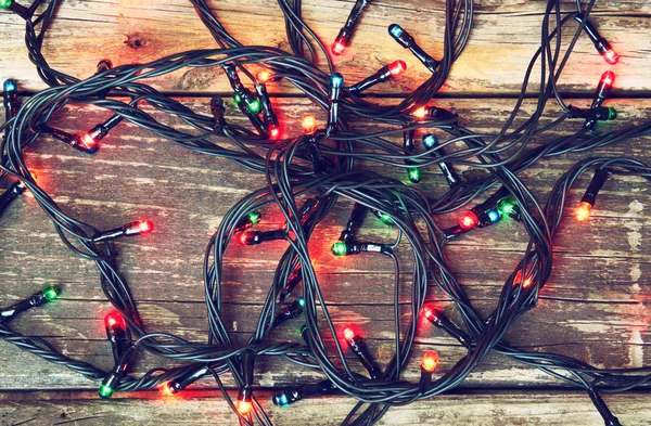 Colorate luci di Natale su sfondo rustico in legno. immagine filtrata — Foto Stock