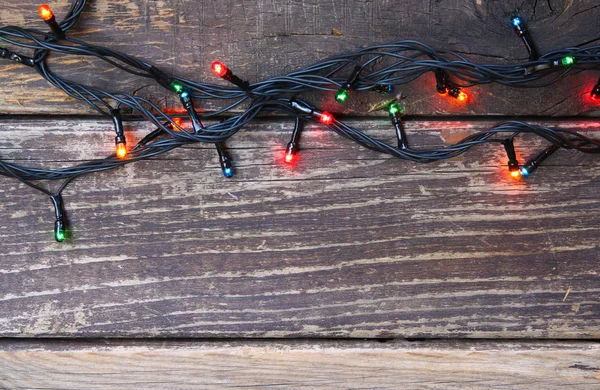 Colorate luci di Natale su sfondo rustico in legno. immagine filtrata — Foto Stock
