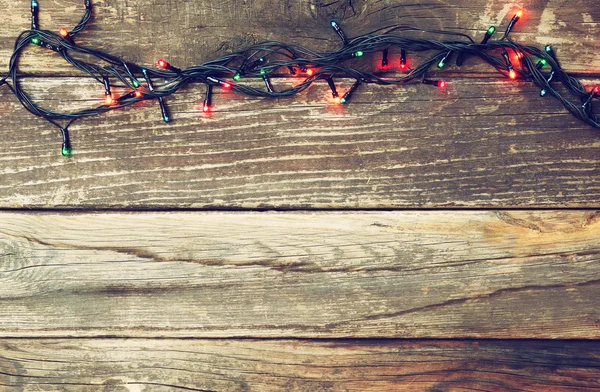 Барвисті різдвяні вогні на дерев'яному сільському фоні. фільтроване зображення — стокове фото