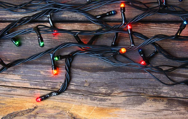 Luzes de Natal coloridas em fundo rústico de madeira. imagem filtrada — Fotografia de Stock