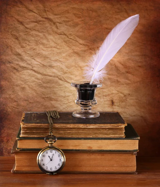 Low key image of white Feather, inkwell and ancient books on old wooden table — Stock Photo, Image