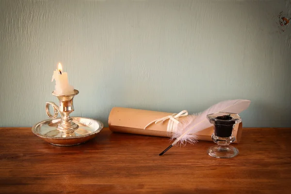 Image basse de plumes blanches, encrier et faire défiler sur une vieille table en bois — Photo