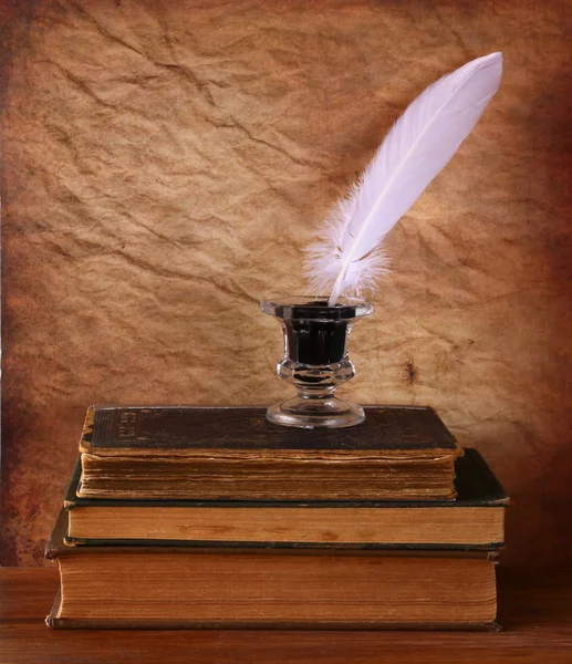 Χαμηλή βασική εικόνα λευκό φτερό, μελανοδοχείο και καίγοντας κερί σε ένα ξύλινο τραπέζι — Φωτογραφία Αρχείου