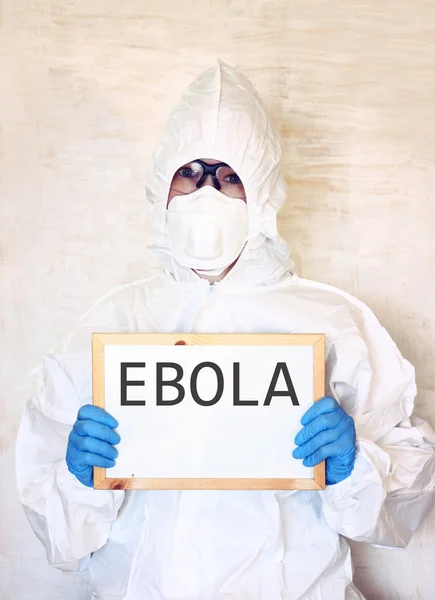 Lab scientist in safety suit holding board with word ebola