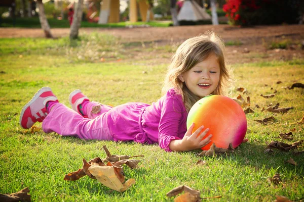 ちょっと素敵な女の子が公園の芝生の上の彼女のボールで遊んでいます。フィルターされたイメージ — ストック写真