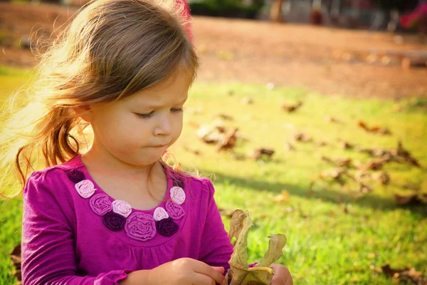 Piccola bella ragazza che gioca sull'erba nel parco. immagine filtrata — Foto Stock