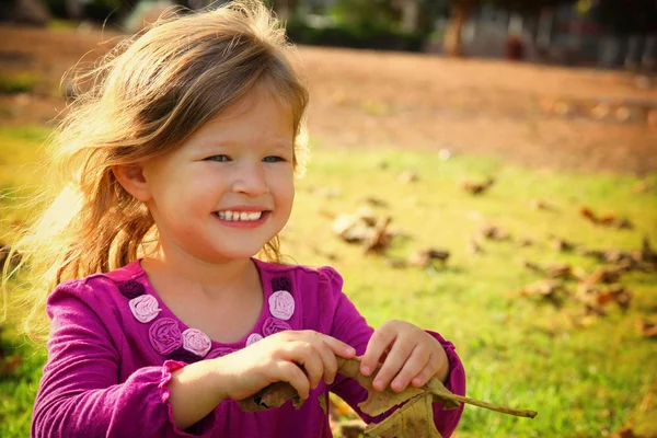 Piccola bella ragazza che gioca sull'erba nel parco. immagine filtrata — Foto Stock