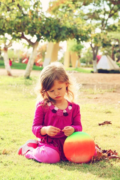 Menina encantadora brincando na grama no parque. imagem filtrada — Fotografia de Stock