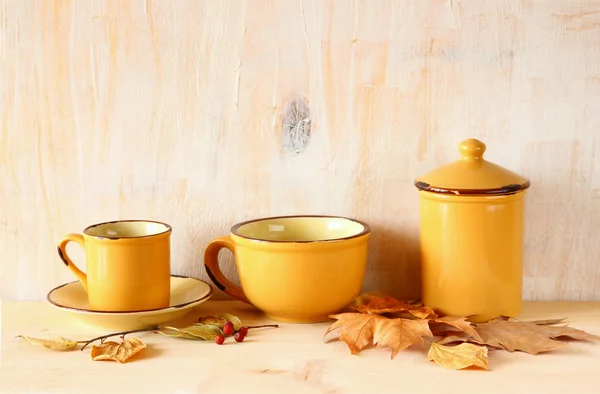 Set de tazas de café y tarro viejo sobre mesa rústica de madera y hojas de otoño. imagen filtrada — Foto de Stock