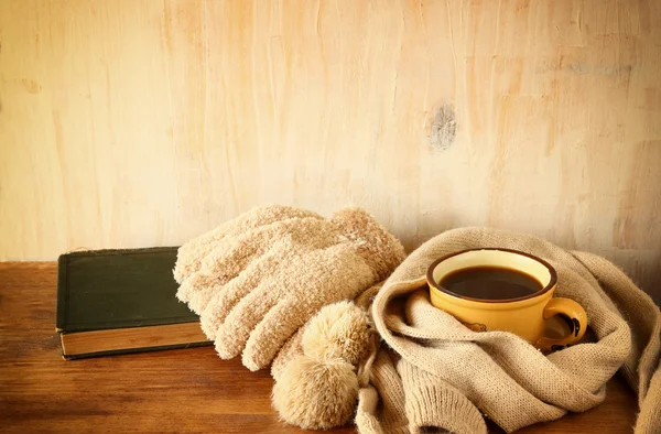 Taza de café negro con una bufanda caliente sobre fondo de madera. imagen filtrada — Foto de Stock