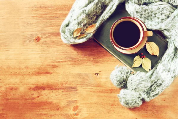 Vue du dessus de la tasse de café noir avec des feuilles d'automne, un foulard chaud et un vieux livre sur fond en bois. image filtrée — Photo