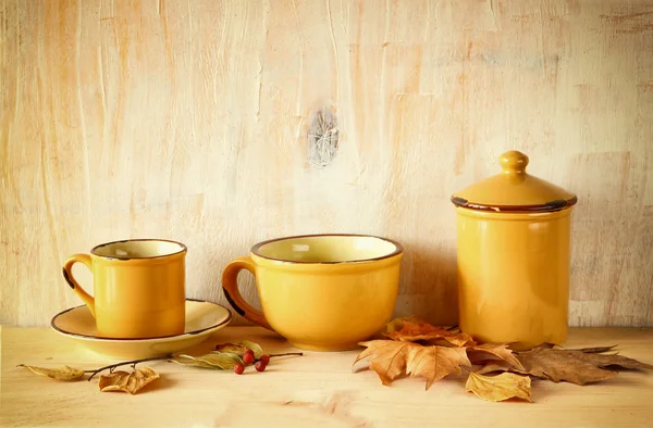 Set de tazas de café y tarro viejo sobre mesa rústica de madera y hojas de otoño. imagen filtrada — Foto de Stock