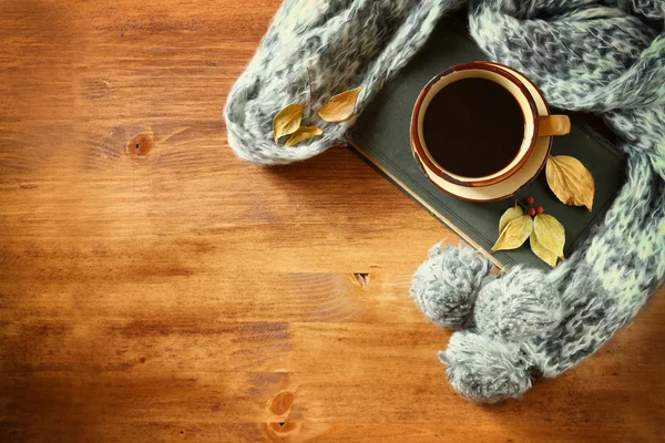 Ovansida av kopp svart kaffe med höstlöv, en varm halsduk och gamla bok om trä bakgrund. filreted bild — Stockfoto