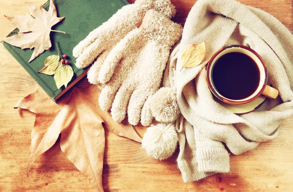 Ovansida av kopp svart kaffe med höstlöv, en varm halsduk och gamla bok om trä bakgrund. filreted bild — Stockfoto