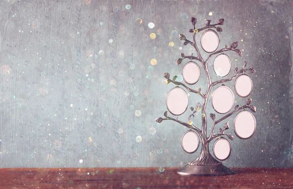 Image of vintage antique classical frame of family tree on wooden table and glitter lights background . filtered image