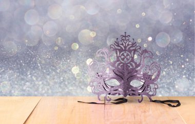 Ahşap masa ve glitter arka plan üzerinde gizemli Venedik maskeli balo maskesi