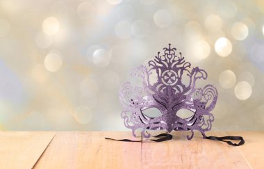Ahşap masa ve glitter arka plan üzerinde gizemli Venedik maskeli balo maskesi