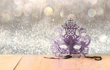 Ahşap masa ve glitter arka plan üzerinde gizemli Venedik maskeli balo maskesi