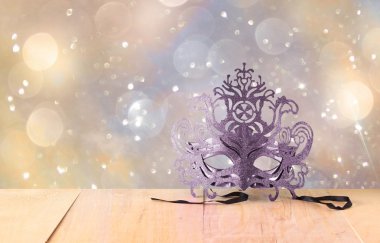Ahşap masa ve glitter arka plan üzerinde gizemli Venedik maskeli balo maskesi