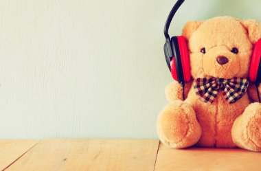 Ahşap masa üzerinde kulaklıklarla bir oyuncak ayı