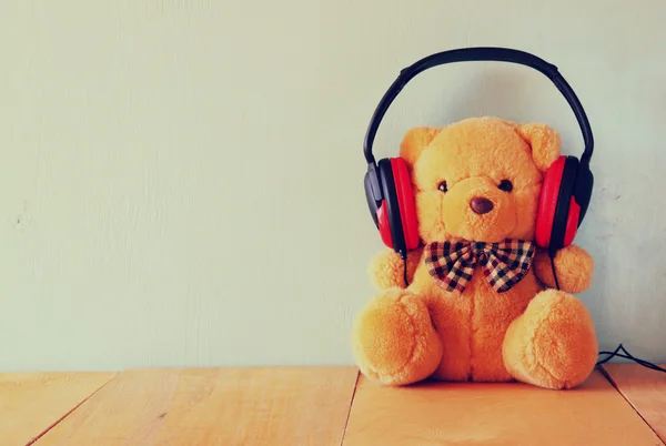 Teddy bear with headphones over wooden table — Stock Photo, Image