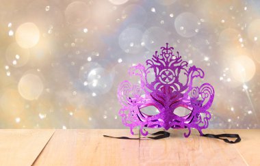 Ahşap masa ve glitter arka plan üzerinde gizemli Venedik maskeli balo maskesi