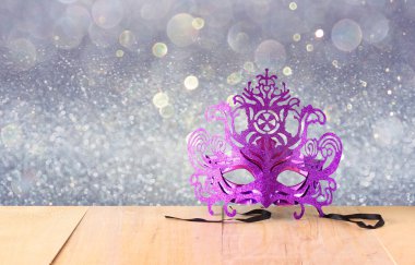 Ahşap masa ve glitter arka plan üzerinde gizemli Venedik maskeli balo maskesi