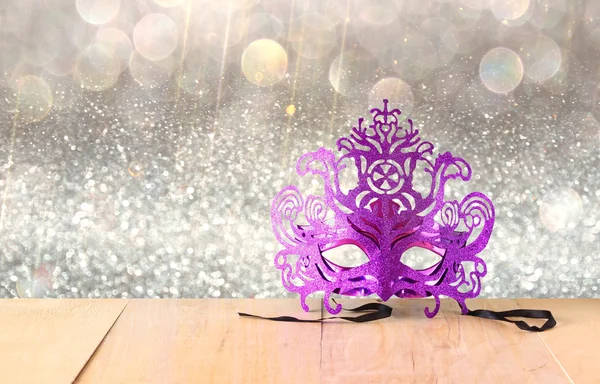 Misteriosa maschera veneziana su tavolo di legno e sfondo glitter — Foto Stock