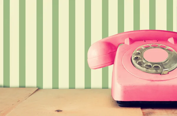 Téléphone rose pastel rétro sur table en bois et motif pastel géométrique rétro abstrait Fond. image filtrée rétro — Photo