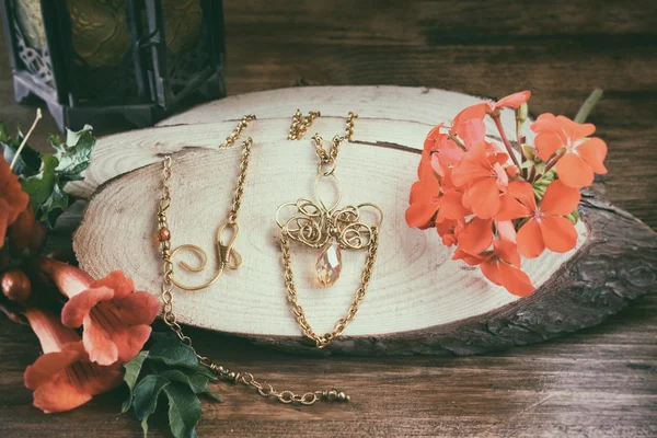 Photo of handmade necklace over wooden table with flowers. retro style image, glamour and style concept — Stock Photo, Image