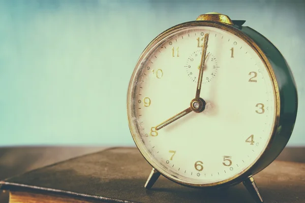 Foto de viejo reloj de alarma sobre mesa de madera, con efecto retro desvanecido — Foto de Stock