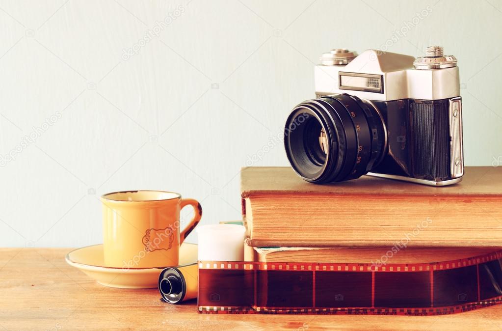 Stack of books and vintage camera over wooden table. image is processed with retro faded style