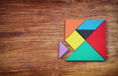 Ahşap masa üzerinde bir kare tangram bulmacanın kayıp bir parça. tarzı fotoğraf soluk