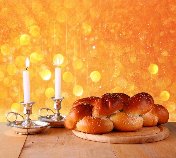 Sabbath image. challah bread and candelas on wooden table. glitter overlay