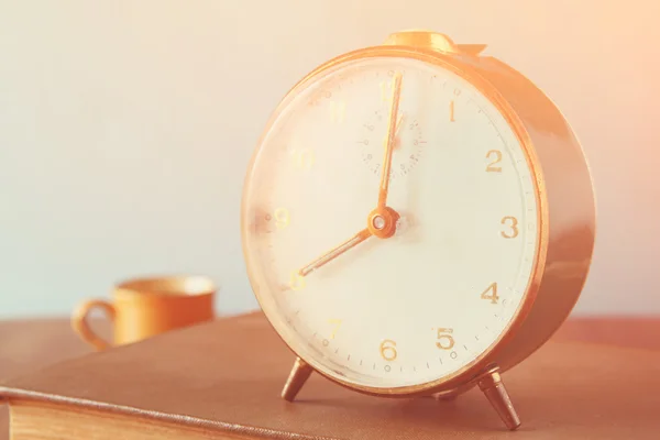 色あせたレトロな効果を持つ、木製のテーブルの上に古い目覚まし時計の写真 — ストック写真