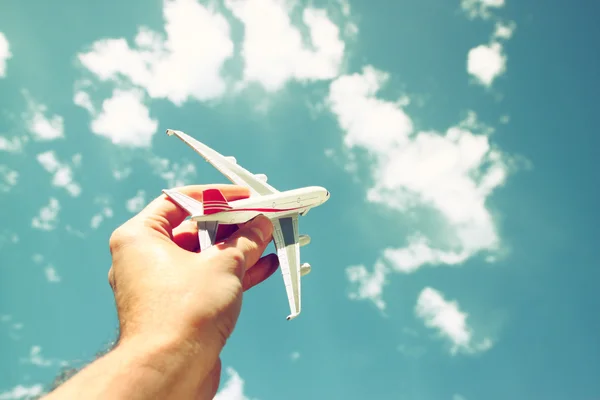 Bir adamın elinde mavi gökyüzü bulutlu oyuncak bir uçağı tutarken çekilmiş bir fotoğrafı. — Stok fotoğraf