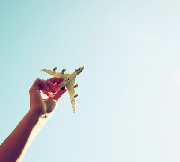 Close up foto da mão da mulher segurando avião de brinquedo contra o céu azul com nuvens — Fotografia de Stock