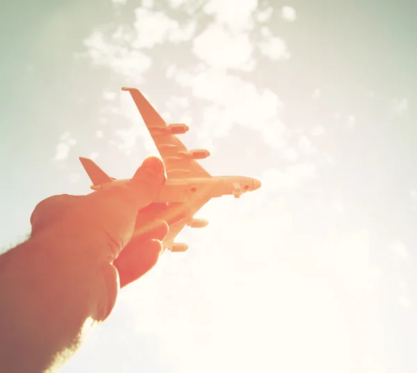 Крупним планом фото рук чоловіка, що тримає іграшковий літак на фоні блакитного неба з хмарами — стокове фото