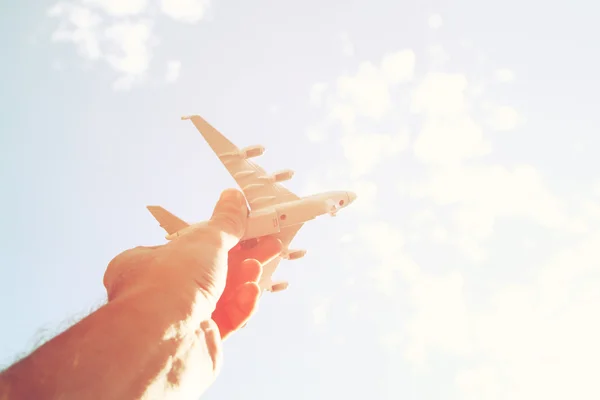 Close up photo of man's hand holding toy airplane against blue sky with clouds — Stock Photo, Image