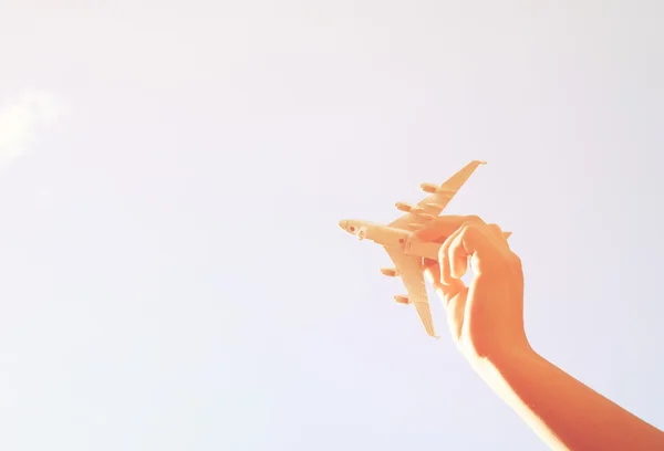 Close up foto da mão da mulher segurando avião de brinquedo contra o céu azul com nuvens — Fotografia de Stock