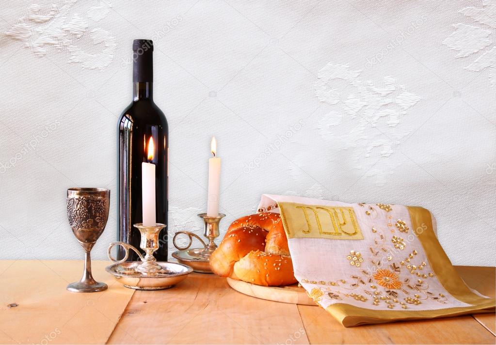 Shabbat image. challah bread, shabbat wine and candelas on woode